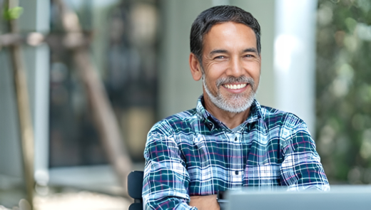 Man in plaid blue shirt folding his arms and smiling at camera.